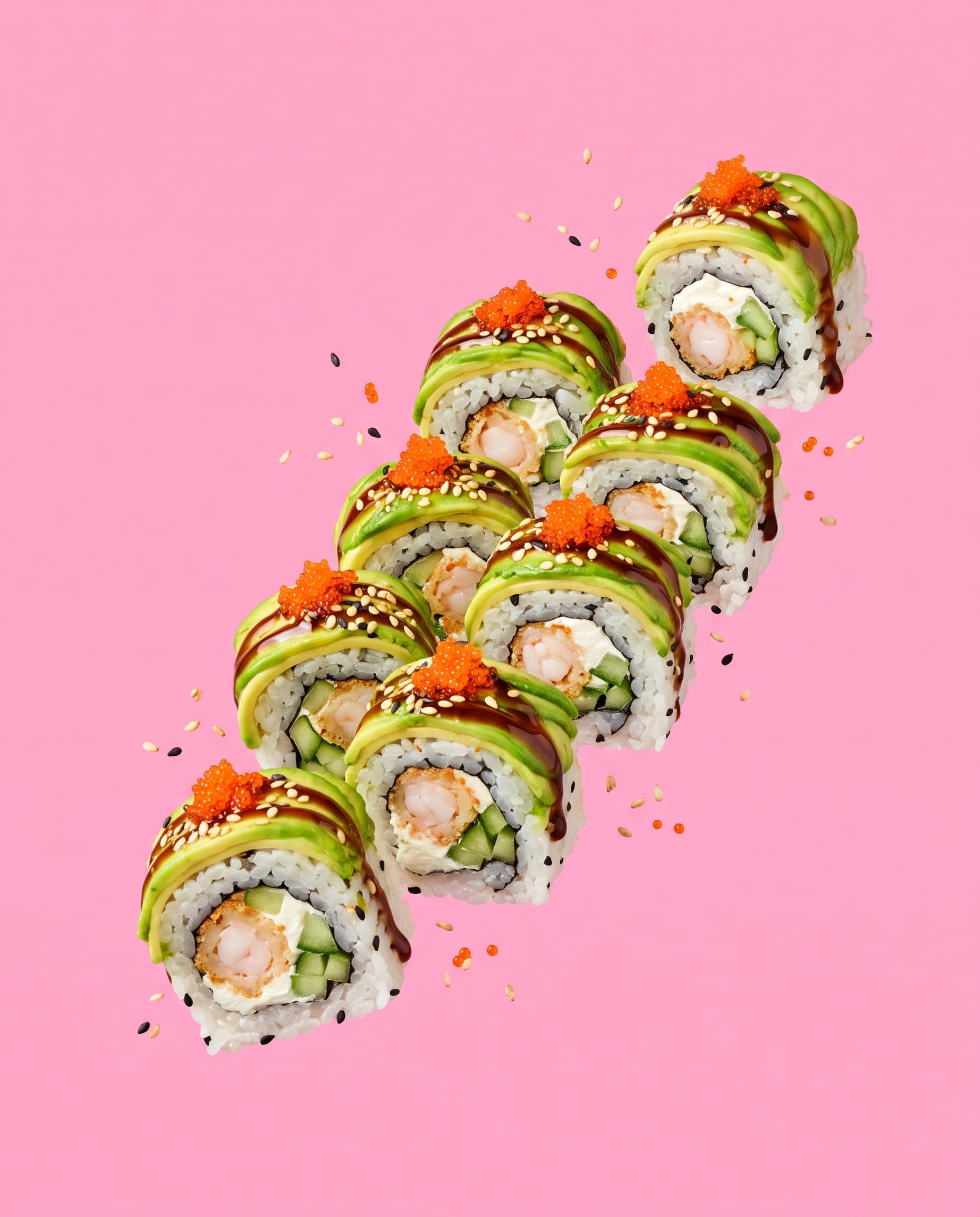 Dragon roll pieces topped with avocado, eel glaze and orange tobiko floating on pink